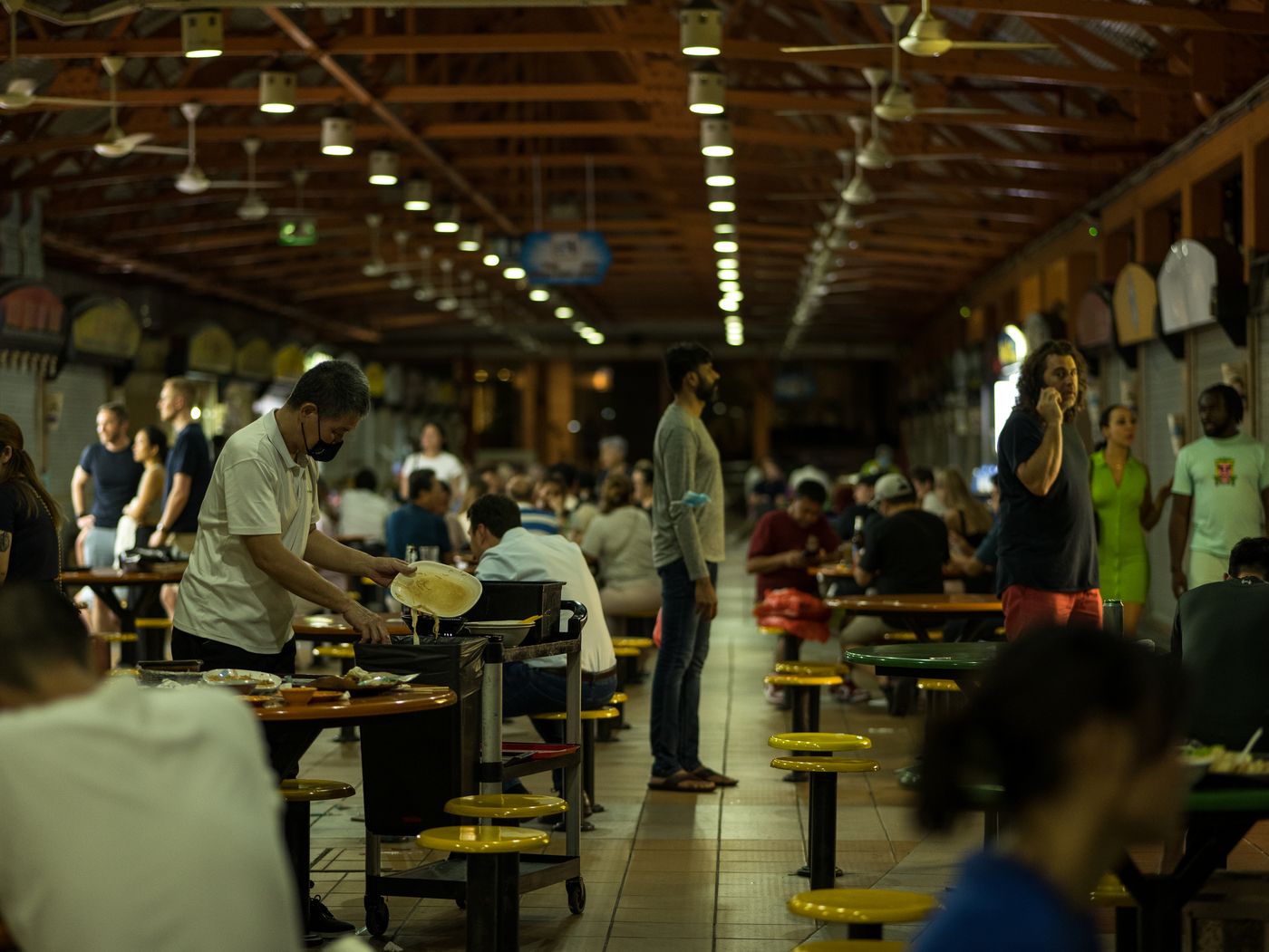 Abends im Hawker Centre, ein Mann räumt Teller ab