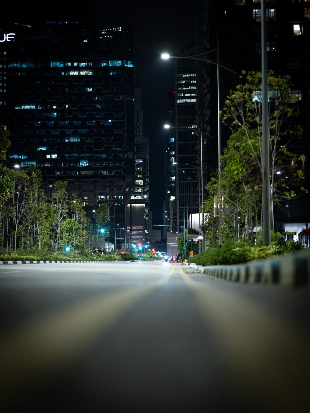 Leere Straße bei Nacht zwischen Bürotürmen, flach über dem Asphalt fotografiert