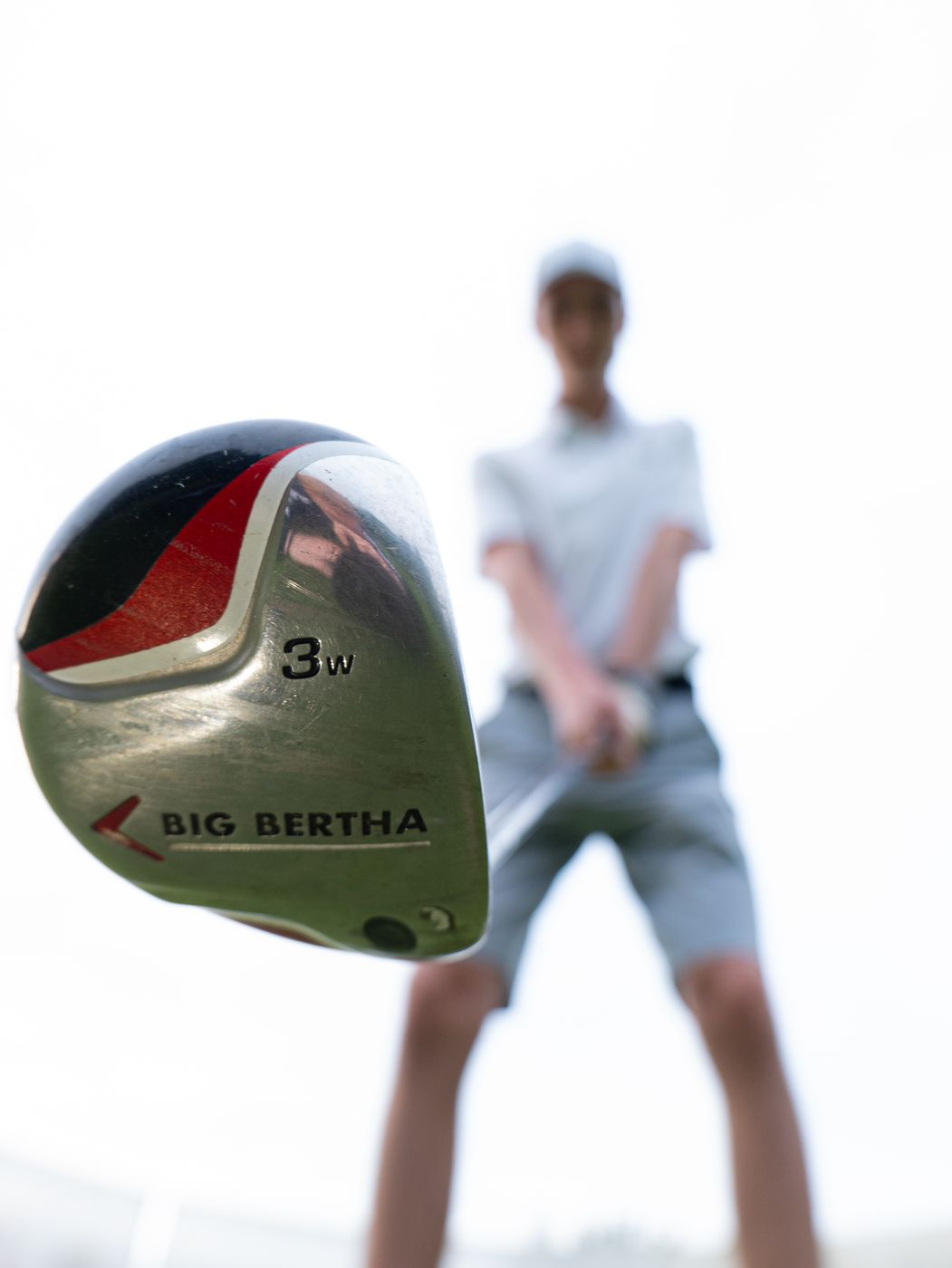 Golfschläger Big Bertha scharf im Vordergrund, Golfer unscharf dahinter