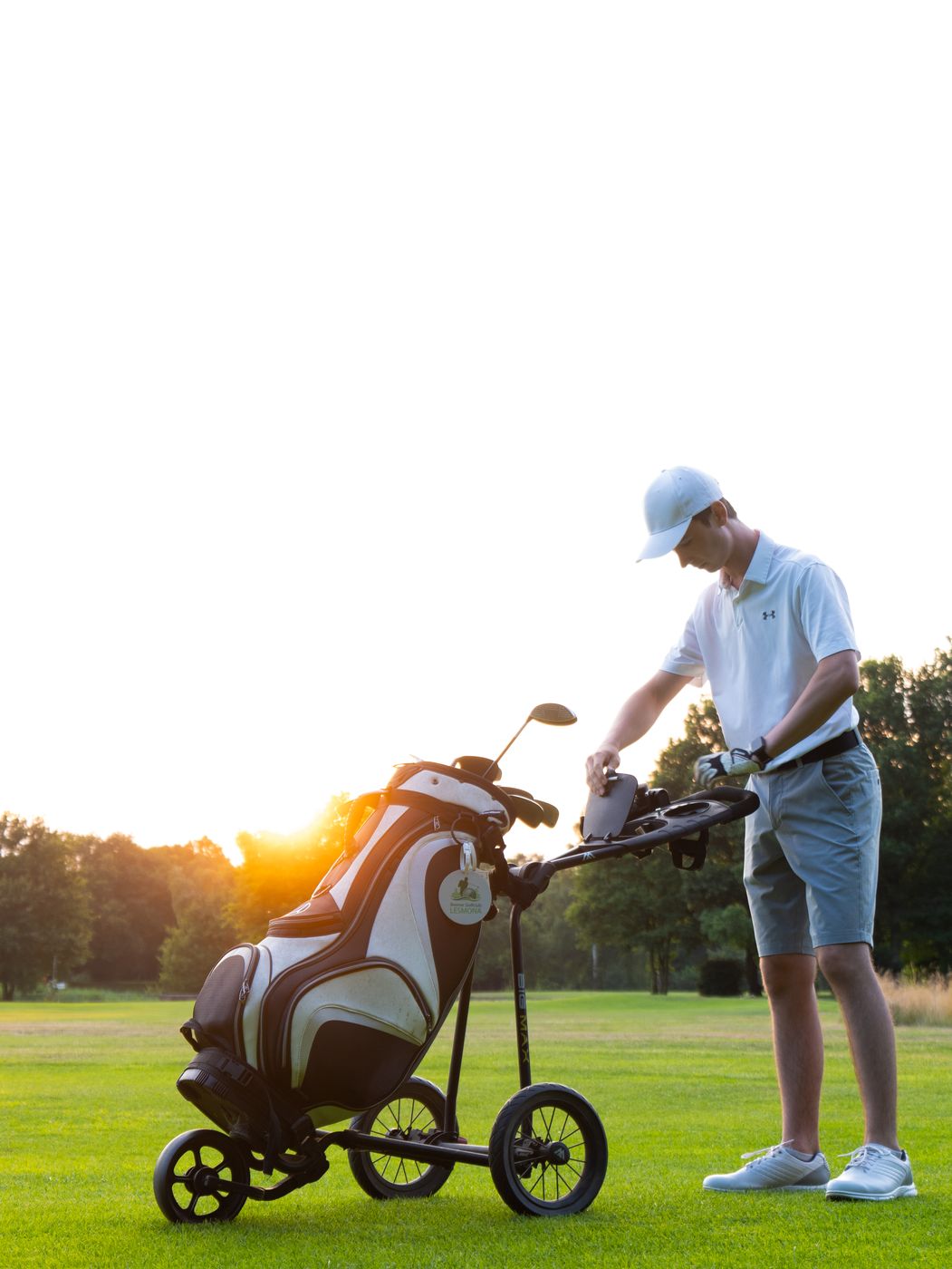 Golfer am Trolley bei Sonnenuntergang